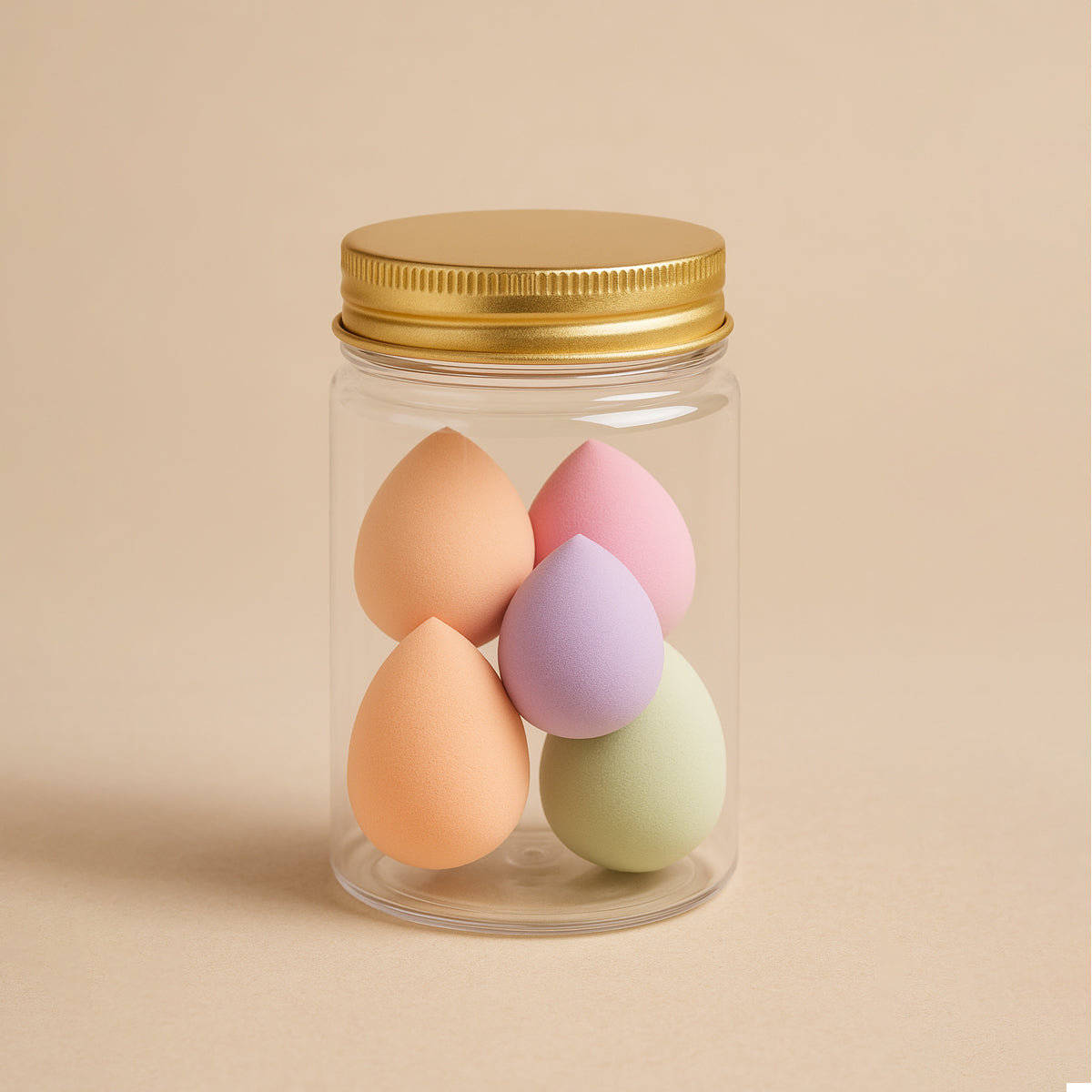 Set of colorful makeup blending sponges in a clear jar with golden lid